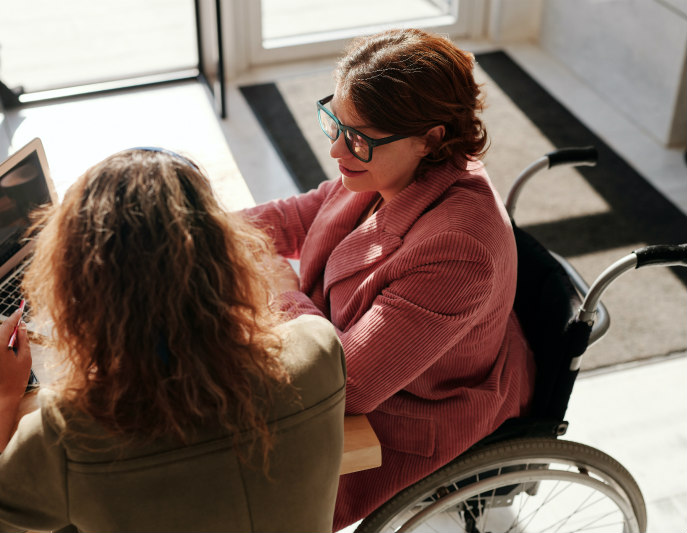 Woman in wheelchair working at desk with colleague